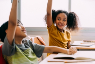 Elementary age Asian student boy raised hands up